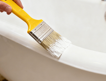 Applying an even coat of DWIL 2K epoxy to a bathtub rim with a paint brush