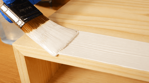 Applying a thin coat of DWIL Wood Furniture Paint with a brush