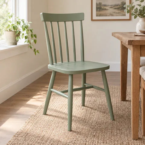 Sage green wooden chair in a sunlit dining room